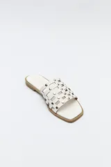 Sandalia baja negra con diseño entrelazado y apliques metálicos.