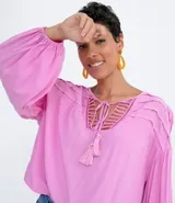 Blusa tipo blusón color rosado, de viscosa, con cuello redondo, manga larga acampanada, pliegues en los hombros, detalle de entredós en el escote y tiras de ajuste con borla.