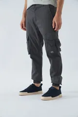 Pantalón cargo gris oscuro, corte slim, con cierre de botón y cremallera, trabillas para cinturón, bolsillos cargo con botón y puños ajustados.