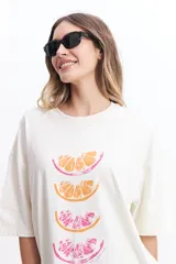Remera blanca de corte amplio con estampado de tres rodajas de naranja y pomelo en tonos naranja y rosa.