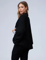 Cardigan negro de tejido suave, estilo poncho o capa, con cuello tipo chal y mangas amplias.