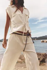 Pantalón de tiro alto color crudo, con cintura elástica, bolsillos delanteros y pernera ancha.