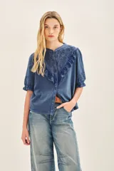 Camisa celeste de algodón con apliques de encaje a tono en pechera y mangas. Cierra con botones de pasta a tono en el frente. Puños con elásticos que generan efecto balloon.