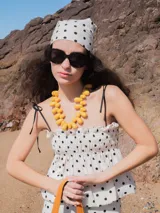 Musculosa blanca con estampado de lunares negros, breteles finos negros y frunce elástico en el busto.