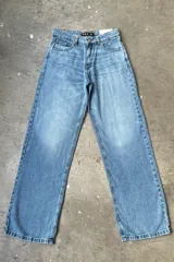 Jean de mezclilla celeste con lavado claro, corte recto o ligeramente holgado, y grandes estrellas plateadas brillantes estampadas en los bolsillos traseros. Posee un parche de cuero marrón con el logo "nox" en la parte trasera de la cintura.