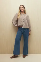 Camisa color crema a rayas verticales finas, de cuello mao, mangas 3/4 abullonadas con elástico en los puños y cierre frontal con botones de nácar.