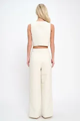 Conjunto color crema de chaleco con botones dorados y pantalón de vestir de tiro alto.