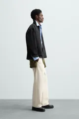 Sobrecamisa color crema de tejido técnico ligero, corte regular fit, cuello solapa, manga larga con puño abotonado, bajo ajustable con elástico en laterales y cierre frontal con cremallera.