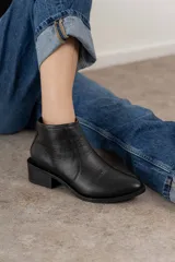 Bota corta negra de cuero, con punta fina y taco cuadrado.