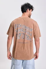 Remera marrón de manga corta con corte oversize y estampa en la espalda con la frase "Each corner of the world has a story to tell".