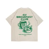Remera oversize color beige con estampado en la espalda de una taza de café con cara sonriente, un cenicero con un cigarrillo y la frase "420 Breakfast Club. Wake and bake everyday".