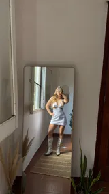 Vestido corto blanco con escote en V profundo y recortes laterales en la cintura. Los breteles son anchos y de material con brillo iridiscente.