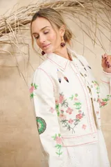 Campera color crema de algodón con estampado de flores, plumas y colibríes, con cuello camisero, cierre frontal con botones metálicos y mangas largas.