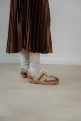 Championes acordonados color beige y dorado con suela marrón.