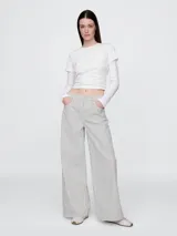Pantalón jean de corte amplio, color crudo con finas rayas verticales negras.