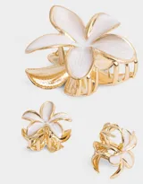Set de tres broches para el pelo de metal esmaltado con forma de flor hawaiana en color blanco y dorado. Incluye un broche grande de 8 cm y dos broches pequeños de 3 cm.