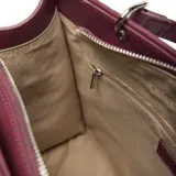 Cartera estructurada mediana color bordó, con solapa frontal que tiene un botón imantado y el logo 'XL' en metal plateado. Posee doble manija fija y correa larga regulable y desmontable.