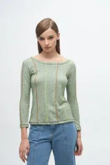 Remera gris de corte ajustado, con cuello redondo y mangas largas. Presenta líneas verticales bordadas en color verde claro y blanco.