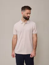 Chomba manga corta color beige con cuello clásico y tapeta de dos botones. Tiene un pequeño logo bordado en el pecho. Corte clásico.