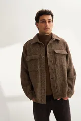 Camisa estilo leñadora marrón con diseño de espiga, cuello clásico, abrochadura frontal a la vista, bolsillos plaqué con tapa en el pecho, mangas largas con puño y botón.