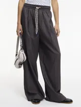 Pantalón recto marrón a rayas metalizadas, con pretina elástica, lazos ajustables y bolsillos laterales funcionales.