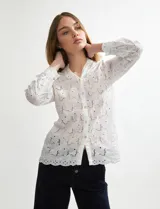 Camisa blanca de manga larga con tejido broderie (ojales bordados) y cuello camisero.