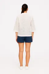 Blusa blanca de algodón con bordado tipo broderie, corte holgado y cuello camisero.