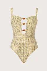 Traje de baño entero con estampado de lunares amarillos y violetas, con escote bandeau y breteles semi-amplios. Presenta cortes circulares con cuentas marrones en el centro y recogidos laterales. Breteles ajustables en la espalda.