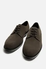 Zapato de vestir tipo derby color marrón oscuro, con capellada de cuero serraje, horma redonda, cordones finos al tono y suela con ligero tacón.