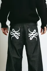 Pantalón de jean negro de corte baggy, con estampado de trigramas blancos en los bolsillos traseros.