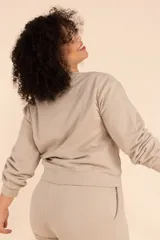 Buzo color beige de corte holgado con cuello redondo y mangas largas.