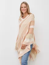 Poncho de tejido de punto color beige y salmón con diseño de rayas diagonales y cuello en V. Presenta terminación con flecos en el ruedo.
