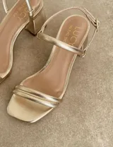 Sandalias doradas de fiesta con tiras finas y taco cuadrado bajo.