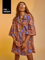 Camisa oversize de algodón con estampado abstracto en tonos marrón, naranja y celeste. Tiene cuello clásico, cierre frontal con botones y mangas cortas.