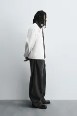 Pantalón de jean celeste con efecto lavado, corte holgado desde la cadera que se estrecha ligeramente en el bajo, tiro medio, cinco bolsillos y cierre frontal con cremallera y botón.