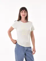 Remera negra de algodón con estampado frontal de la palabra "MERCI" en letras delineadas con colores del arcoíris.