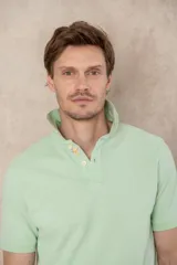 Remera tipo polo color beige, de manga corta y corte clásico. Tiene cuello con botones y está confeccionada en algodón.