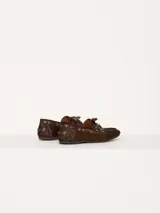 Zapato estilo mocasín acordonado, confeccionado en pelo color marrón con interior forrado en cuero vacuno. Lleva apliques metálicos en níquel.
