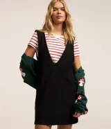 Vestido corto negro de poliéster, con breteles anchos, escote V delantero y trasero y bolsillos grandes.