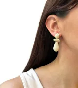 Aros colgantes con diseño geométrico en color beige, con forma de círculos y gotas.