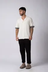 Camisa de tejido de punto color beige, con cuello tipo bowling, manga corta y corte relajado. Cierre frontal con botones.