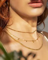 Set de tres gargantillas doradas de diferentes largos. La primera es una cadena de eslabones rectangulares, la segunda es una cadena fina con dijes rectangulares colgantes y la tercera es una cadena gruesa de eslabones apretados.