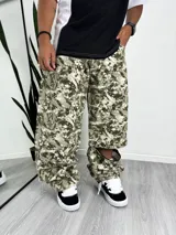Pantalón ancho de estilo cargo con estampado camuflado en tonos verde oliva, beige y blanco. Presenta cierres a la altura de la rodilla que permiten convertirlo en short.