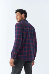 Sobrecamisa de algodón para hombre con interior de corderito, estampado a cuadros en tonos negro, blanco y azul. Tiene cierre de botones, bolsillos tipo cartera y logo en goma. El modelo usa talle M.