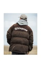 Campera puffer marrón con parte superior de pana y bordado blanco en la espalda con la palabra "Chingona". Tiene tiras regulables en la cintura.