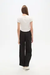 Pantalón de algodón negro, holgado, de calce medio, con cintura elástica y cordón ajustable. Presenta tres rayas blancas verticales en los laterales.