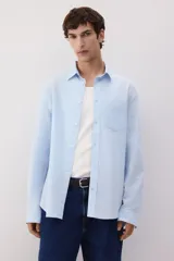 Camisa celeste de lino y algodón, corte regular, manga larga, cuello inglés, bolsillo en el pecho y cierre con botones.