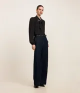 Blusa negra de crepé con cuello con lazo, mangas largas y pliegues en los hombros.