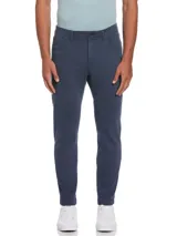 Pantalón azul de gabardina con cinco bolsillos, cierre y botón en la cintura. Tiene remaches metálicos en los bolsillos y aplique de cuero con logo en la parte trasera. Calce slim taper fit, más holgado en cadera y muslos, afinándose hacia el tobillo.