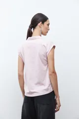Remera de manga corta color rosa pálido, con cuello polo y escote en V con detalle de bordado en el borde.